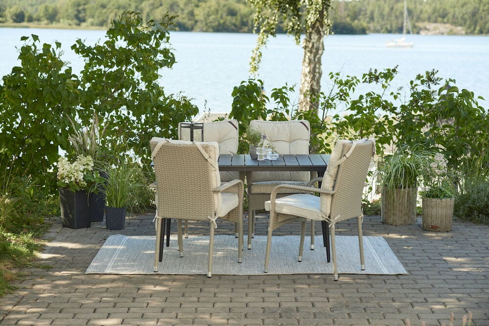 Neljä tuolia, joissa on vaaleanharmaat pehmusteet ruokapöydän ympärillä ulkona.