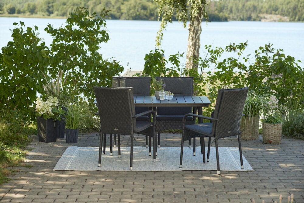 Svarta dynor på utemöbler vid bord utomhus.