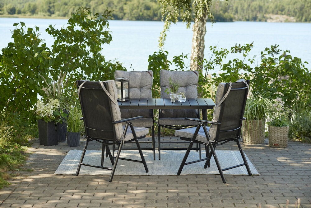 Neljä harmaata tyynyä ulkotuoleilla pöydän ympärillä.