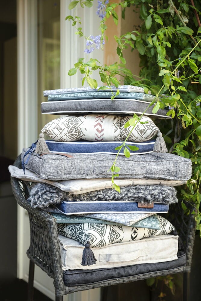 Erilaisilla kuvioilla varustettujen ulkotuolityynyjen pino.