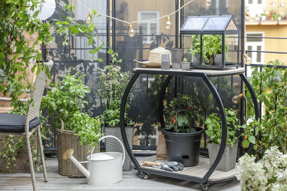 Serveringsvagn i svart metall med trädgårdstillbehör.