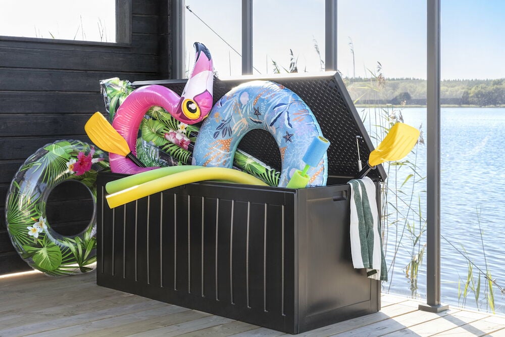 Svart förvaringslåda med badleksaker och handduk.