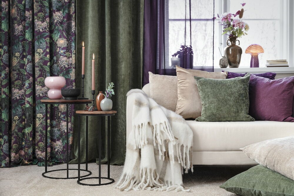 Mörkgrönt kuddfodral i vintage stil på soffa.