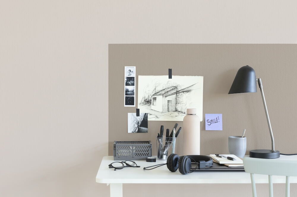 Skrivbord med lampor mot beige vägg med målade ytor.