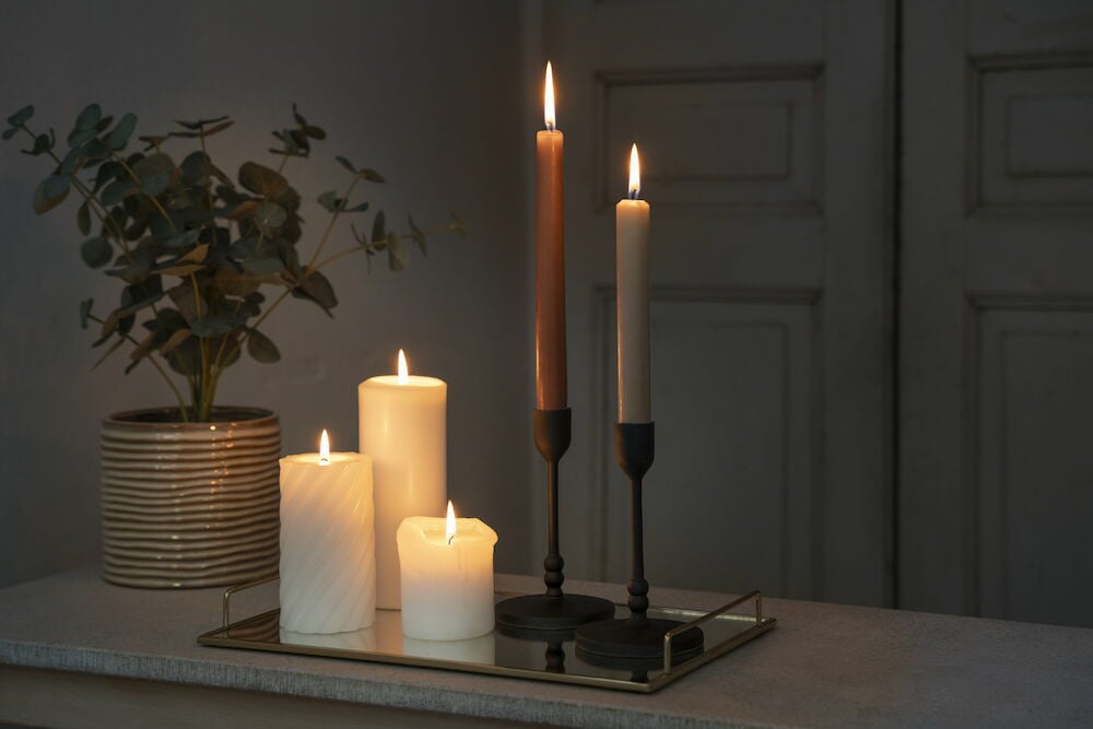 Tre vita blockljus brinner på ett dekorationsfat.