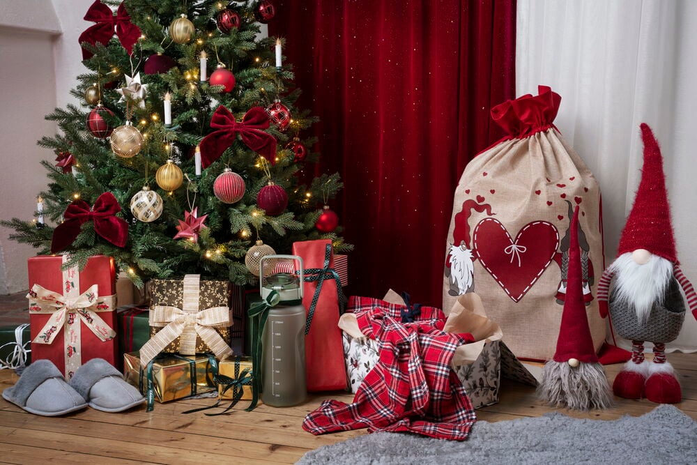 Julklappar och juldekorationer under gran med paketpåse.