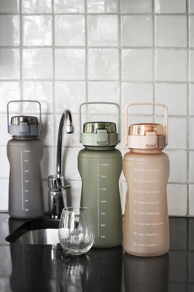 Tre vattenflaskor i olika färger vid diskho.