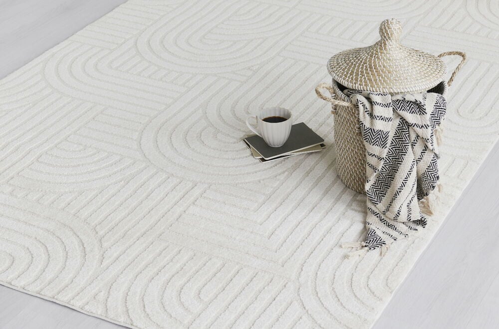 Off-weiße Baumwollplaid neben Korb und Kaffeetasse.