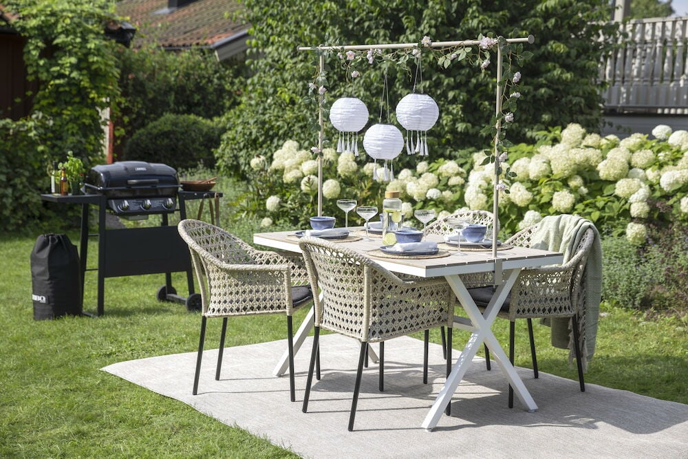 Vitt rektangulärt bord med fyra stolar utomhus.
