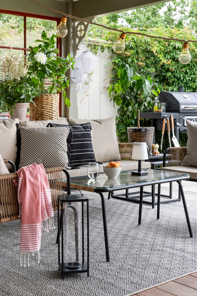 Brun kruka i flätad konstrotting med växt.