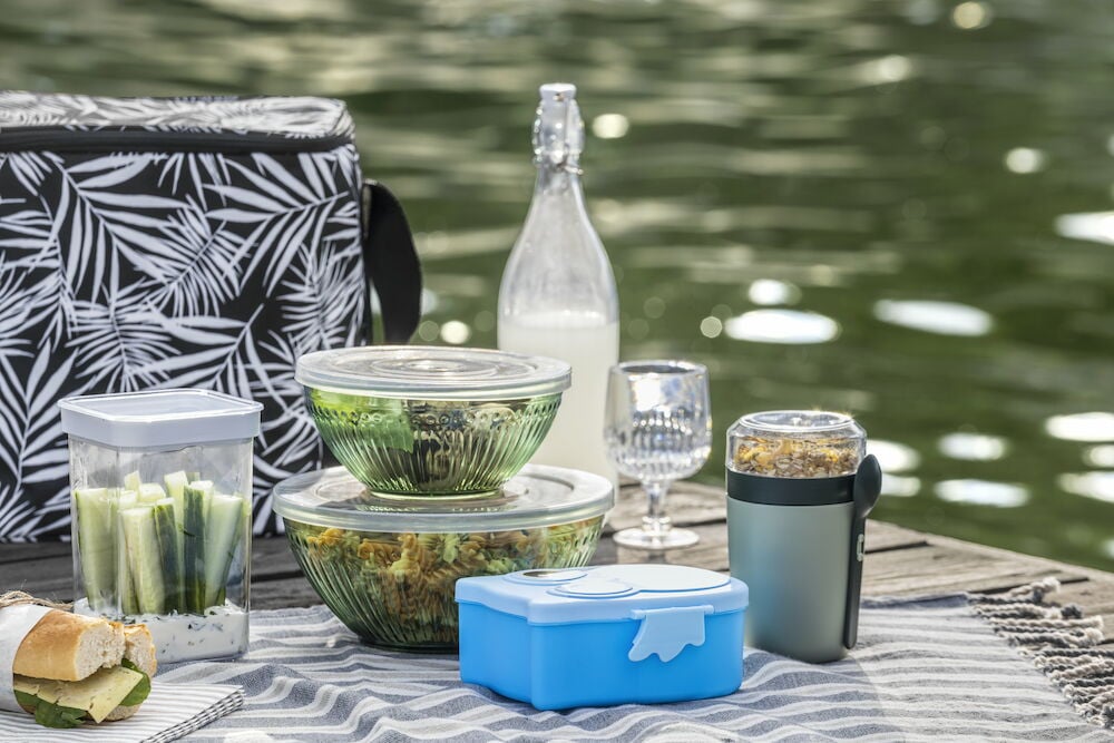 Lasipullo, jossa on panttikorkki, on piknikpeitolla.