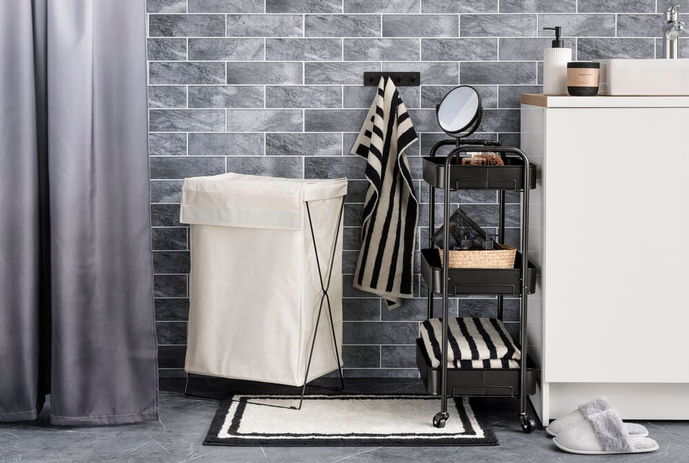 Grått duschdraperi i polyester vid kaklad badrumsvägg.