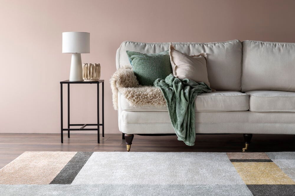 Ljusrosa sidenmatt vägg bakom soffa med kuddar.