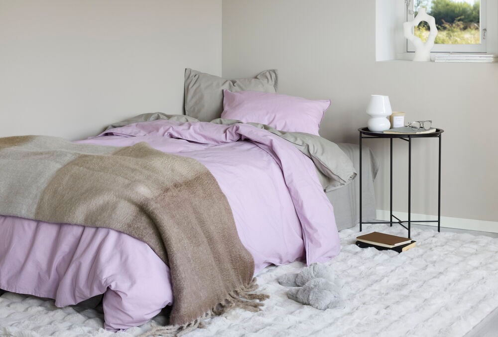 Ljusbeige fluffig matta under säng i sovrum.