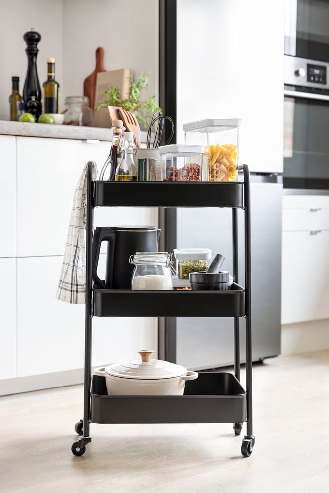 Svart rullvagn med tre hyllor och hjul.