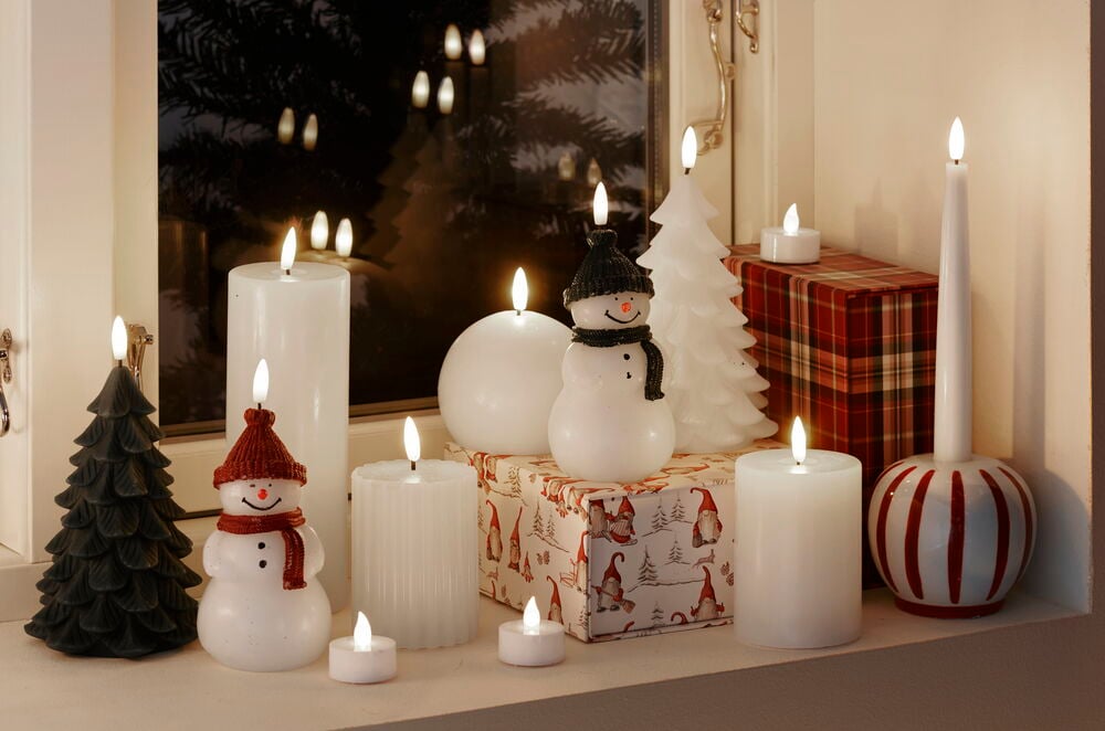 Flera vita LED blockljus på fönsterbräda med dekorationer.