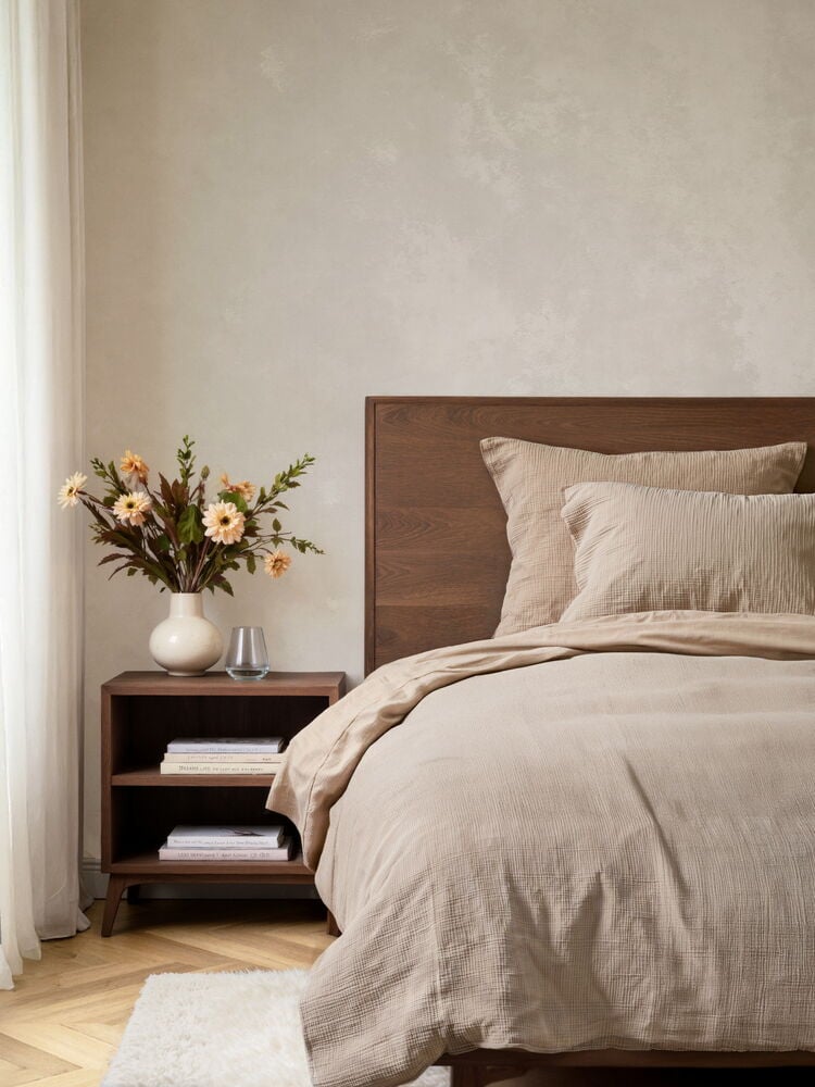 Beiges Baumwoll-Musselin Elsaform Bettwäsche-Set, mit Bettbezug und zwei Kissen, auf dunklem Holzbett.