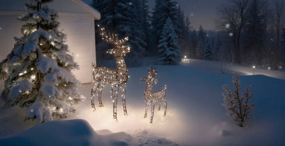 Zwei beleuchtete Dekorationsbeleuchtung Reindeer Cupid, ein großes und ein kleines, mit warmweißen LEDs im Schnee.