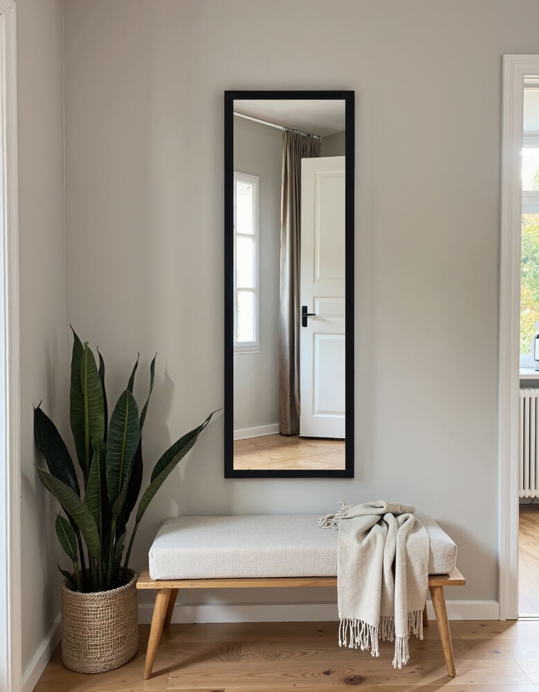 Rektangulär svart spegel på vägg ovan bänk.