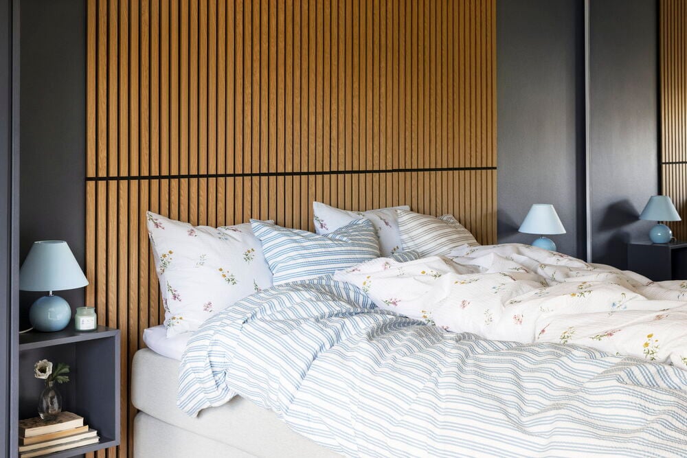 Bäddad säng med blommigt och randigt bäckebölja påslakan.