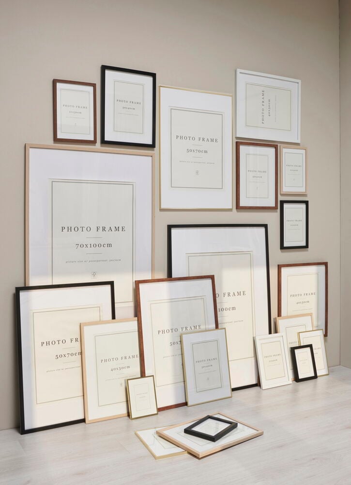 Mehrere Bilderrahmen in verschiedenen Größen an einer beigen Wand.