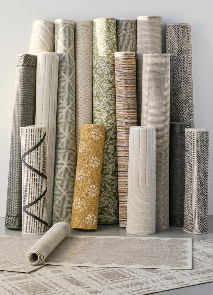 Useita beigejä ja harmaansävyisiä rullattuja käytävämattoja.