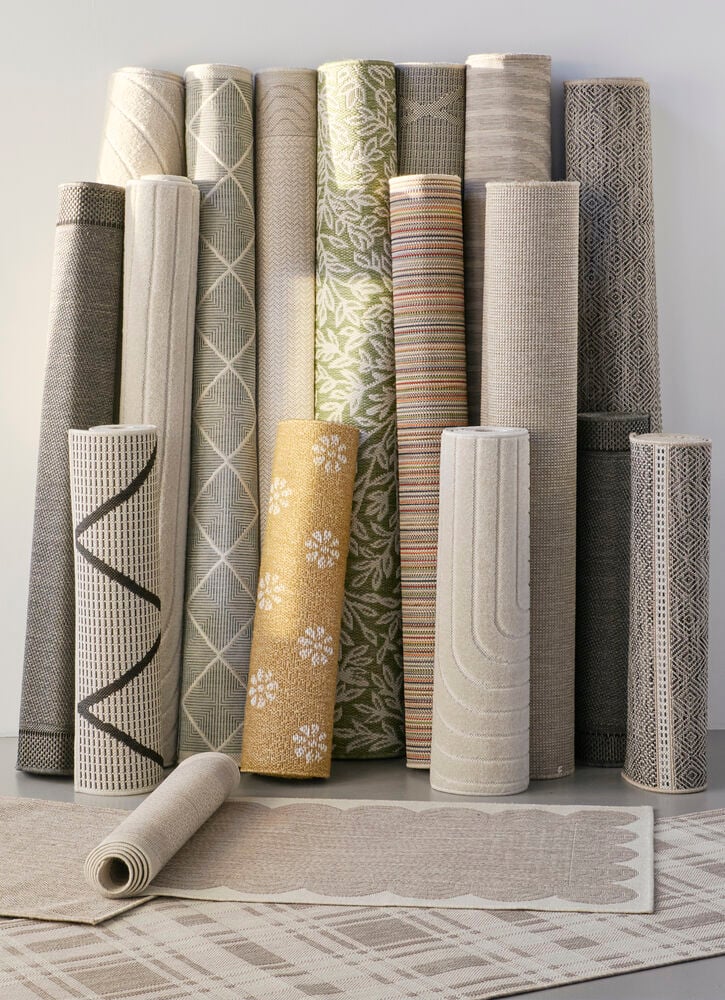 Useita rullattuja mattoja eri kuvioissa ja väreissä.