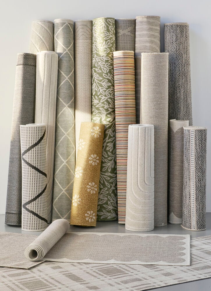 Useita käärittyjä käytävämattoja eri kuvioilla ja väreillä.