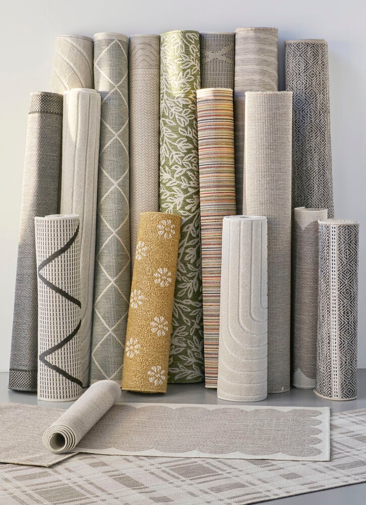 Useita rullattuja mattoja eri väreissä ja kuvioissa.