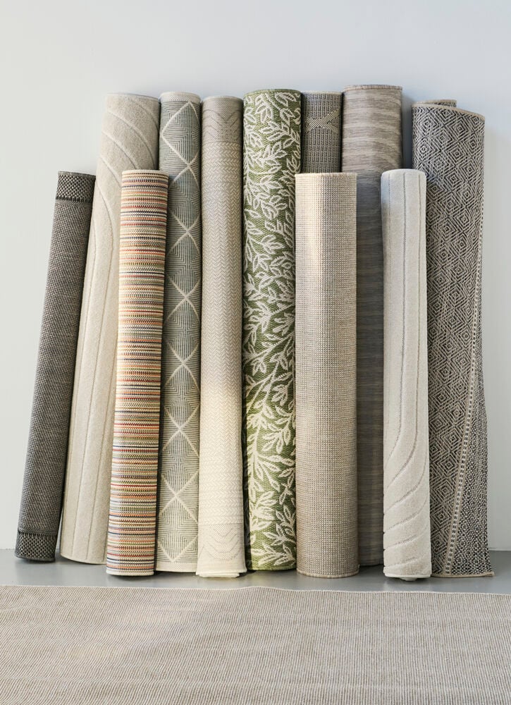 Useita rullattuja mattoja eri väreissä ja kuvioissa.