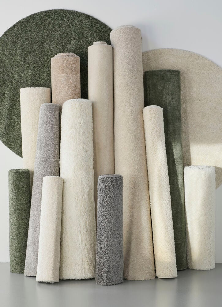 Flera upprullade mattor i olika ljusa och gröna nyanser.