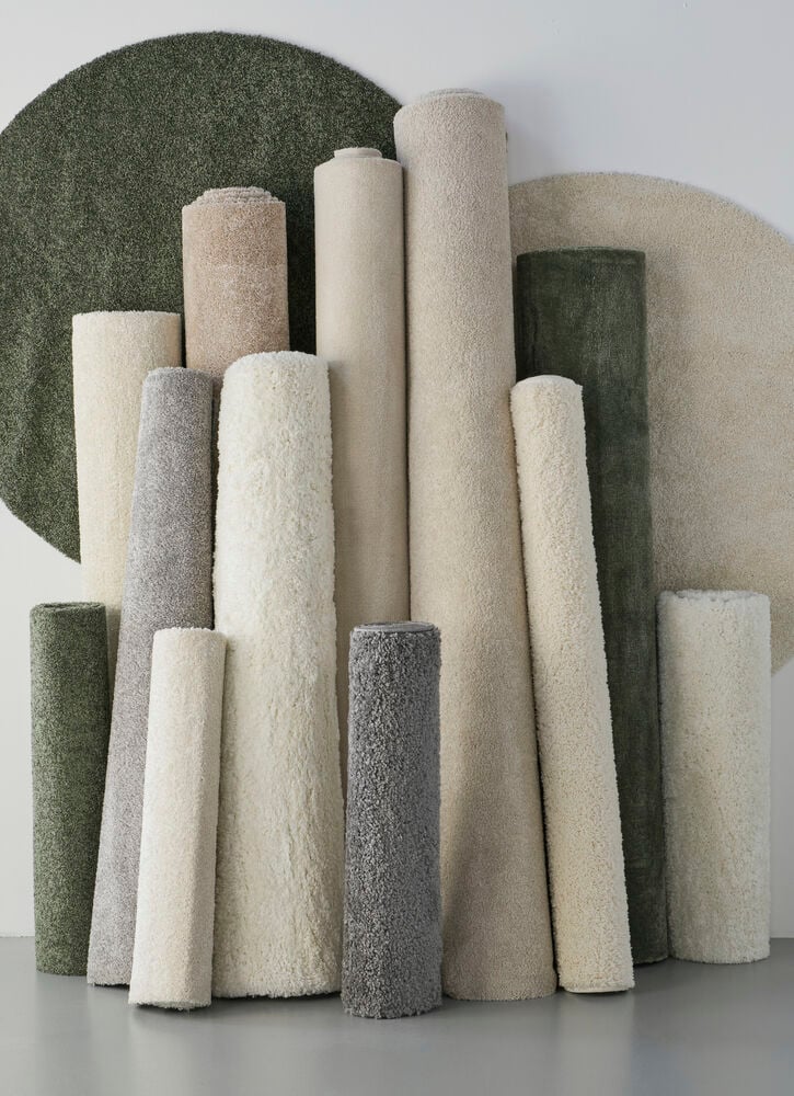 Flera rullade mattor i ljusa och gröna nyanser.