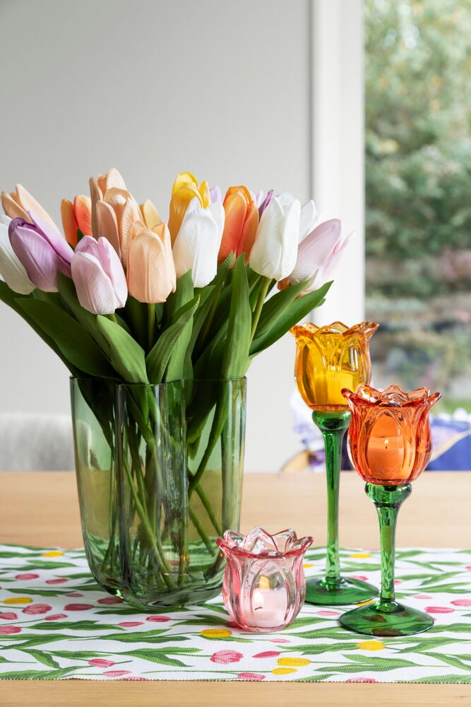 Valkoinen pöytäliina tulppaanikuviolla puupöydällä.