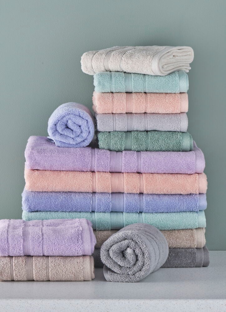 Vikta och rullade handdukar i pastellfärger på hylla.