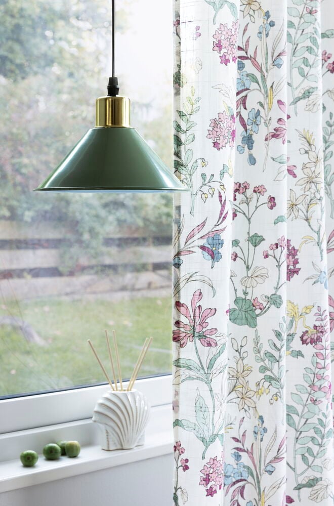 Vita gardiner med färgglatt blommönster vid fönster.