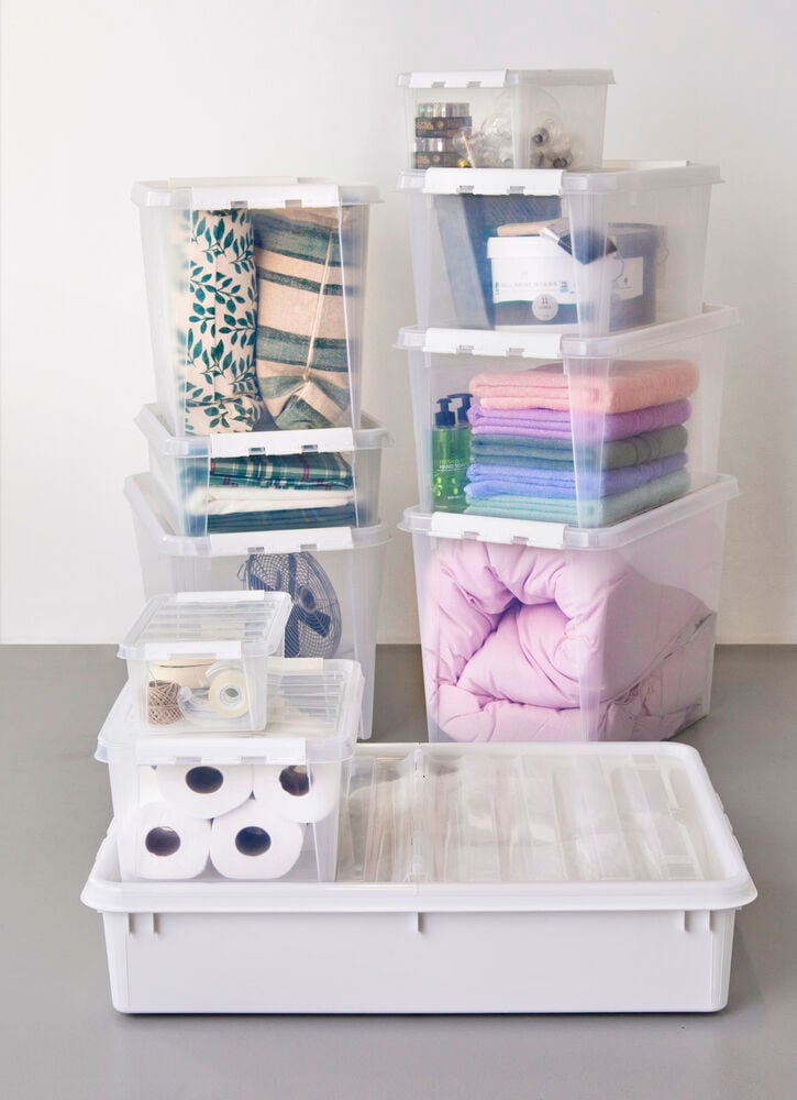 Flera transparenta lådor med lock staplade och organiserade.