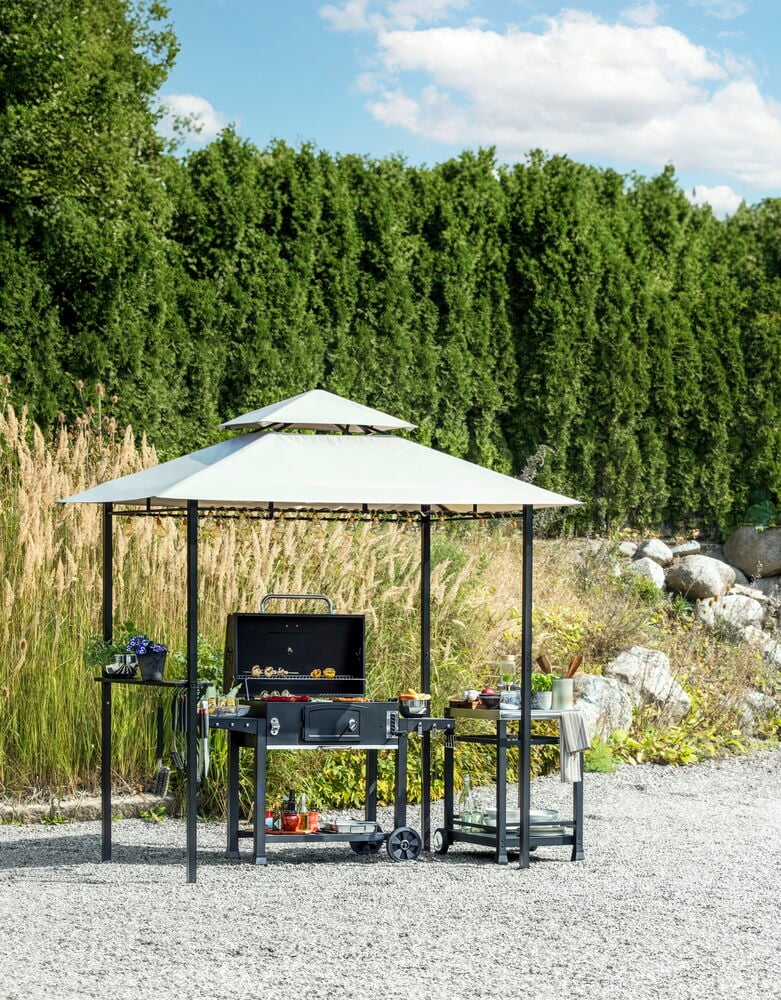 Svart grillvagn med hjul under paviljong utomhus.
