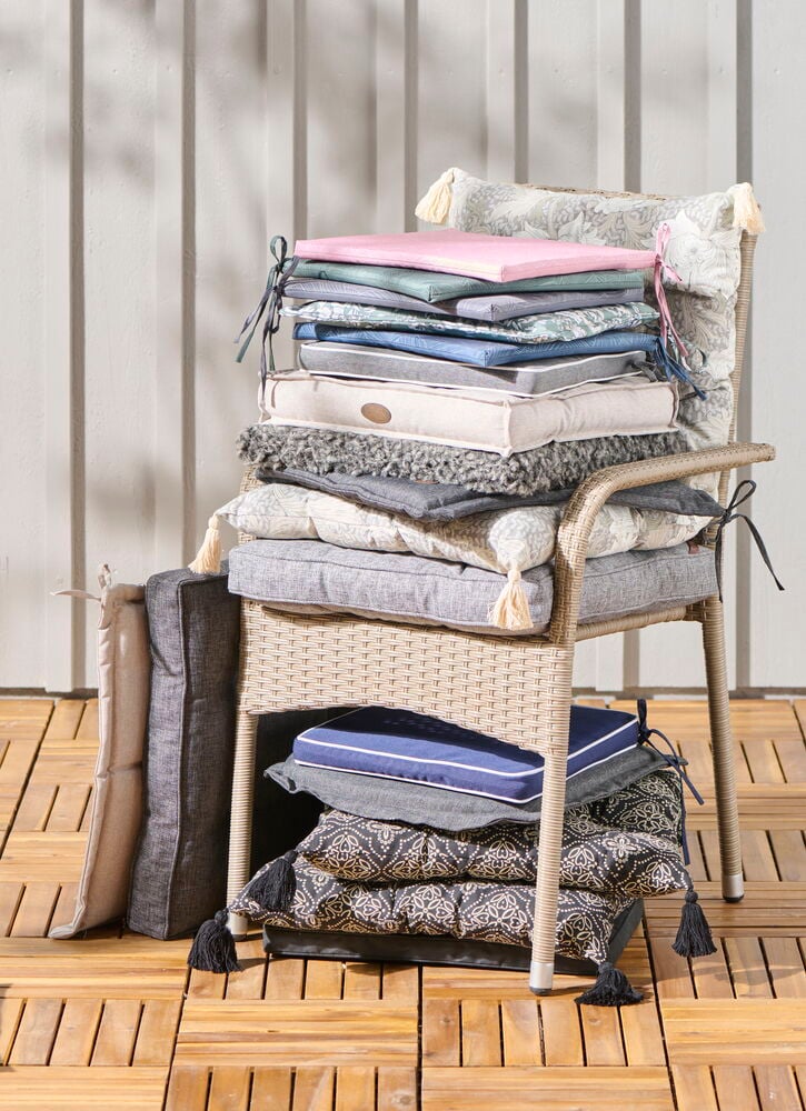 Useita erivärisiä tuolityynyjä pinottuna tuolin päälle.