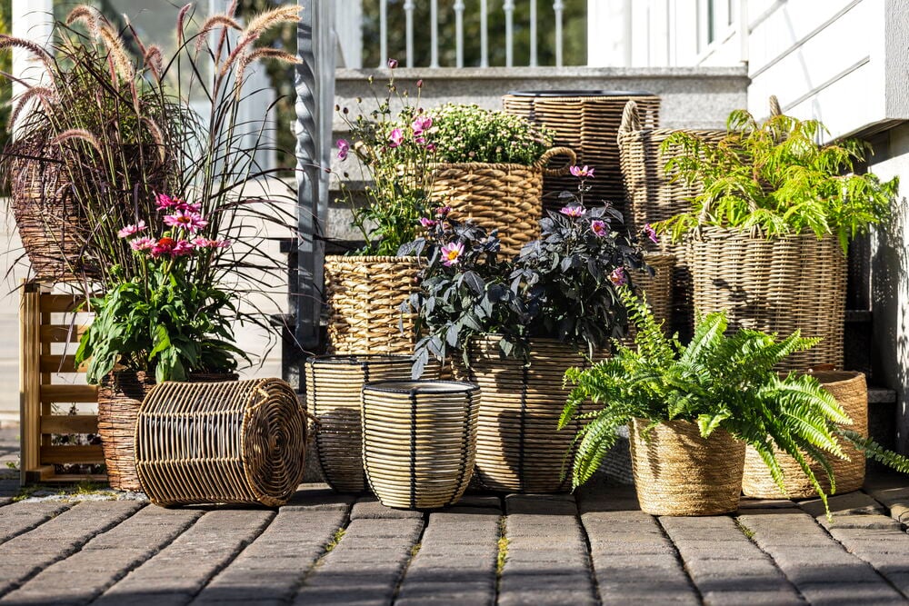 Flere kunstrottingkrukker med grønne og blomstrende planter.