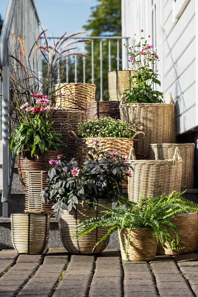 To kunstrottingkrukker med planter utendørs på trapp.