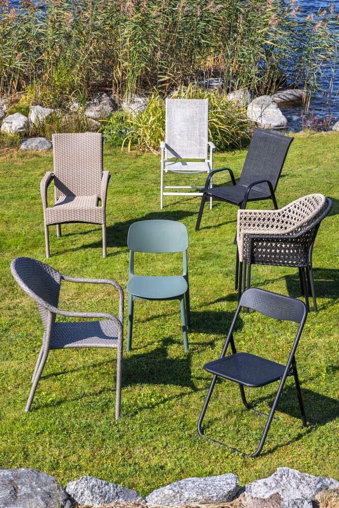 Musta taitettava teräksinen kahvilatuoli nurmikolla.
