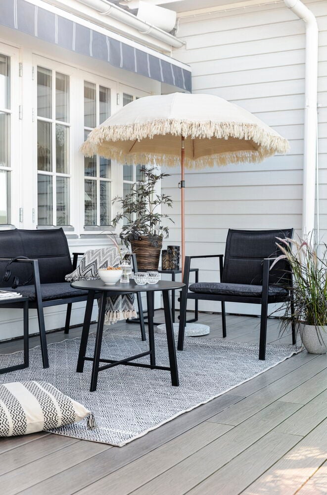 Musta oleskelukaluste pöydällä ja tyynyillä terassilla.