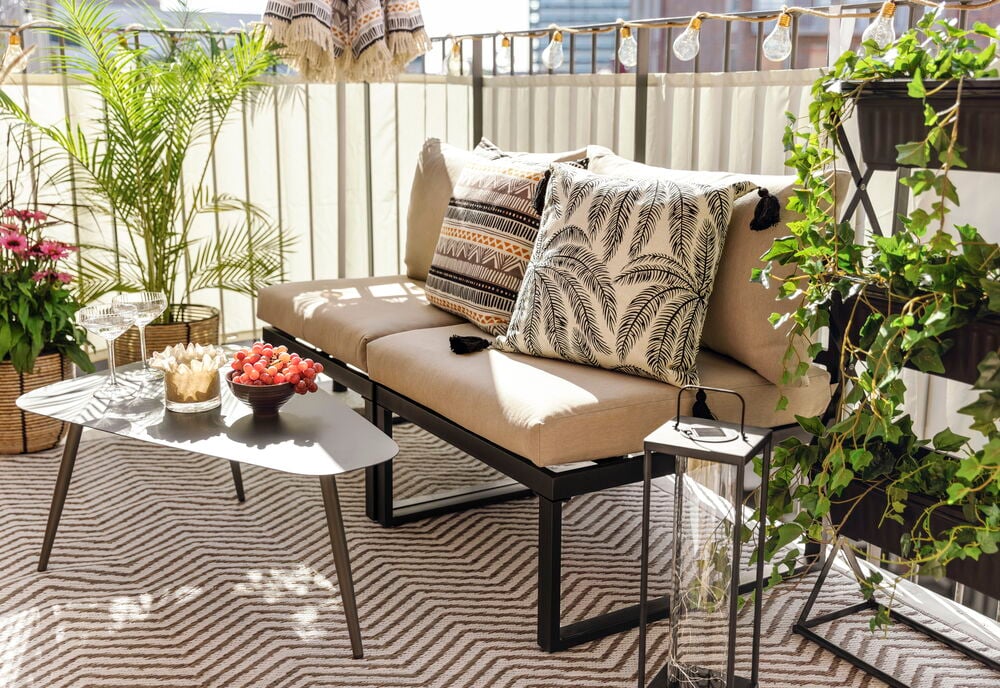 Svart växthylla med tre hyllplan och gröna växter.