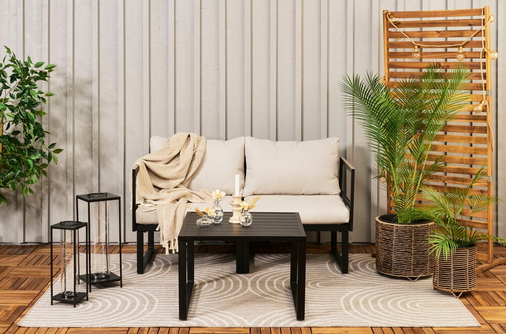 Zwei runde Töpfe aus braunem Kunstrattan mit Pflanzen.