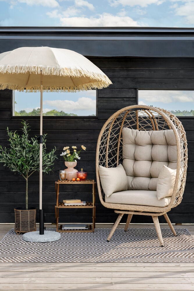 Kaksi rottinkijäljitelmäistä ruukkua aurinkovarjon vieressä.