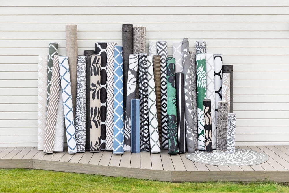 Flera ihoprullade svarta och mönstrade mattor utomhus.