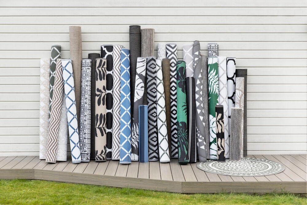 Useita rullattuja muovimattoja eri kuvioilla ja väreillä.