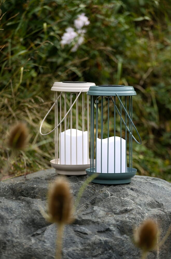Zwei Solarlaterne Resö 24 cm, eine beige und eine dunkelgrüne, stehen auf einem grauen Felsen in der Natur.