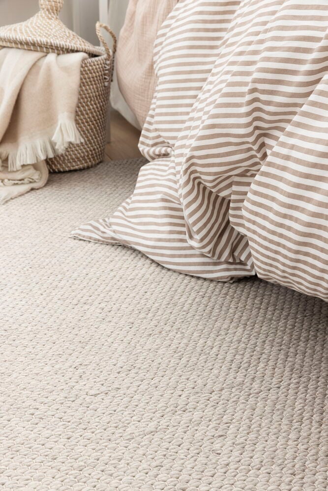 Elsaform Agnes Teppich aus Wollgemisch, natur, mit beige-weiß gestreifter Bettdecke, geflochtenem Korb, beiger Decke.