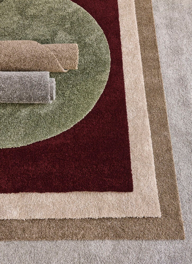 Beige Polypropen Lizette gångmatta bland gröna, vinröda, bruna och grå ryamattor, samt två rullade mattor.